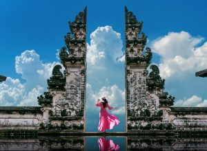 Young woman standing in temple gates at Lempuyang Luhur temple in Bali, Indonesia. Vintage tone.